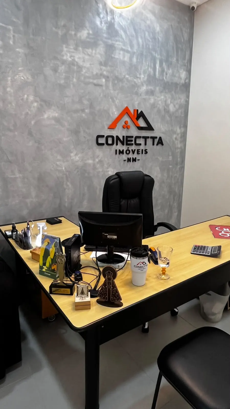 Mesa de atendimento da Conectta, com a marca em relevo na parede